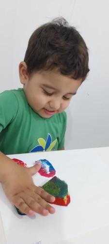 berçário criando lindas borboletas coloridas com carimbos de esponja.